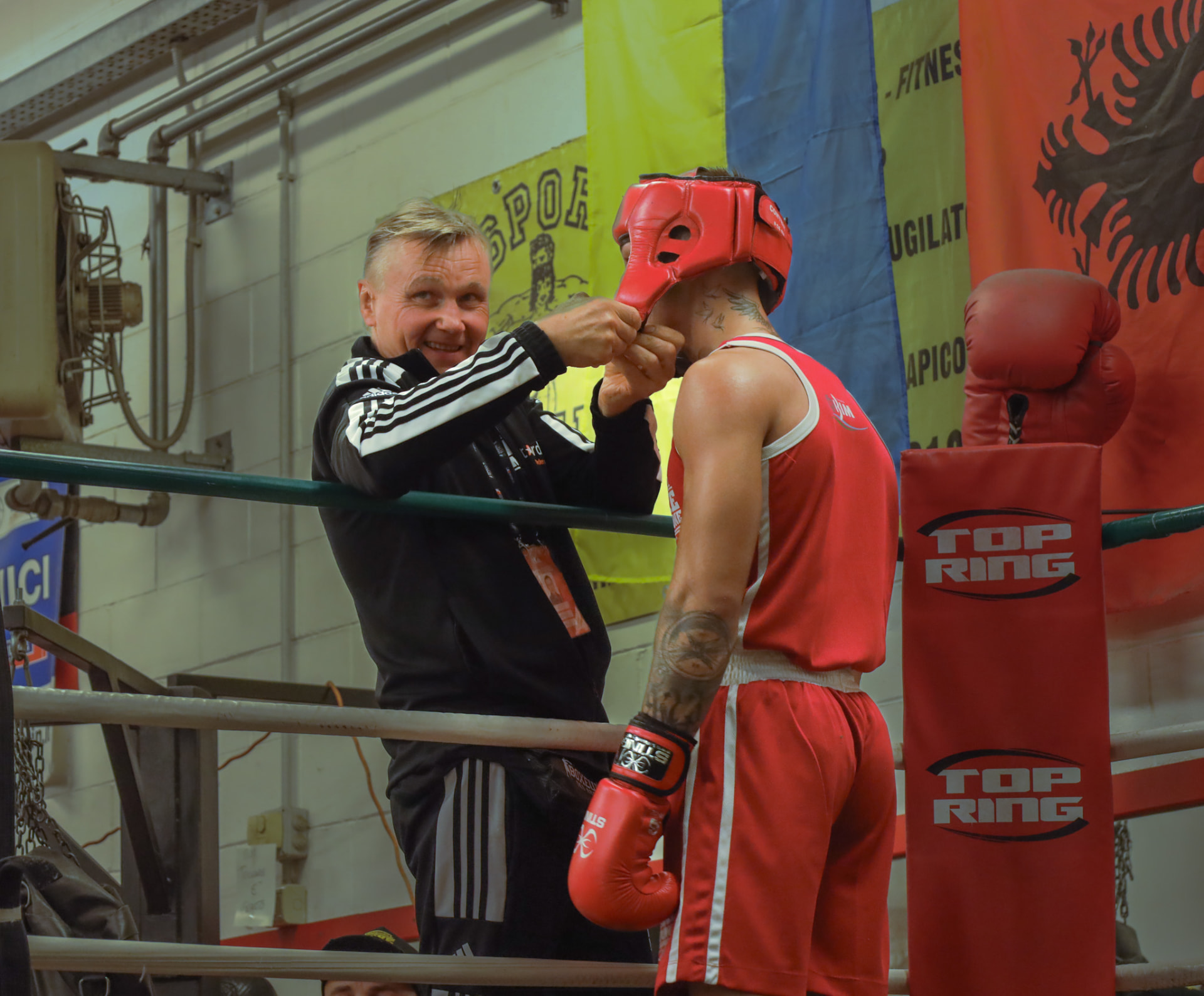 Coach fastening a fighter's red headgear ringside