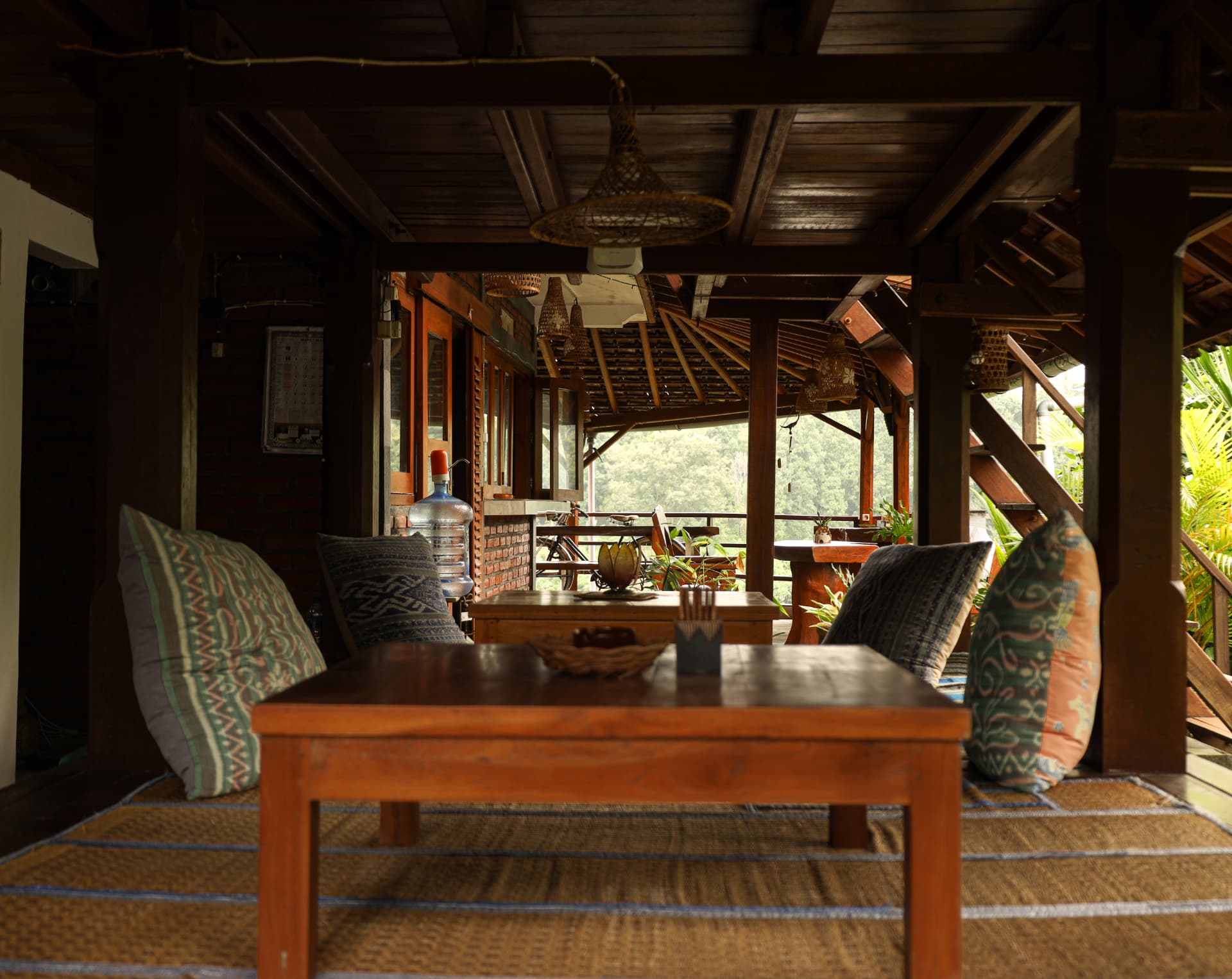Open-air teak lounge with woven rugs and patterned cushions