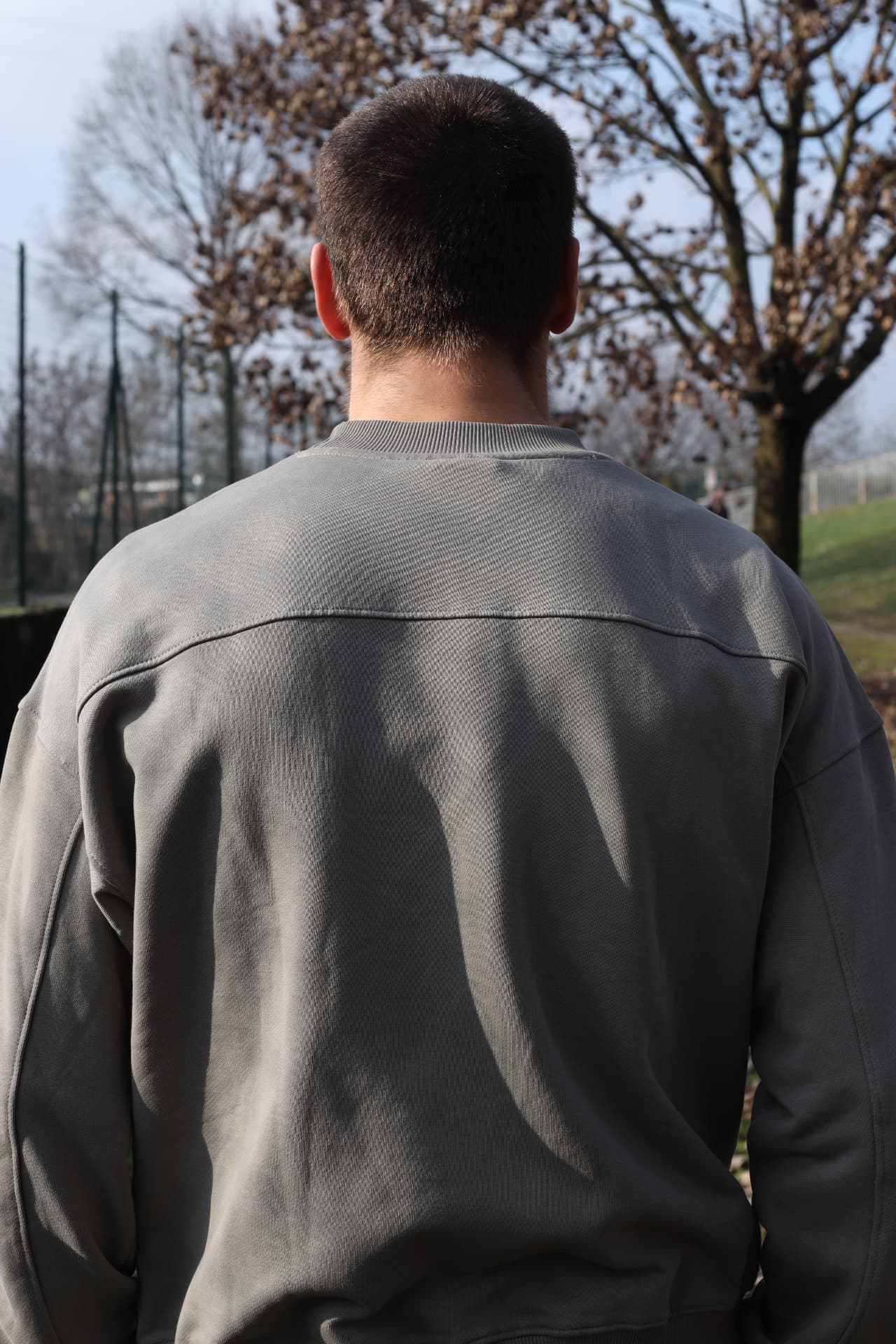 Portrait from behind of a man in a grey sweatshirt in a winter park
