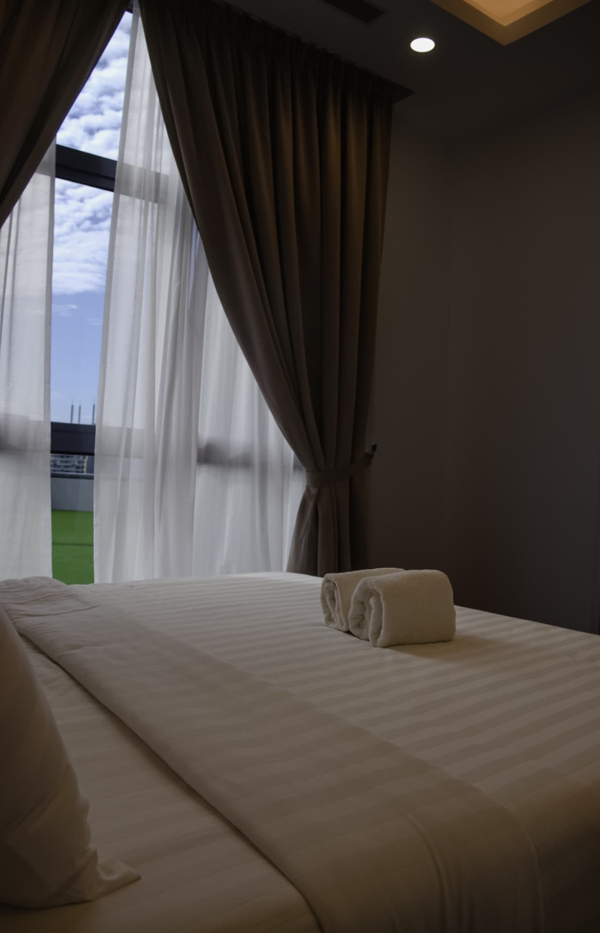 Bedroom detail with rolled towels and morning light through the curtains