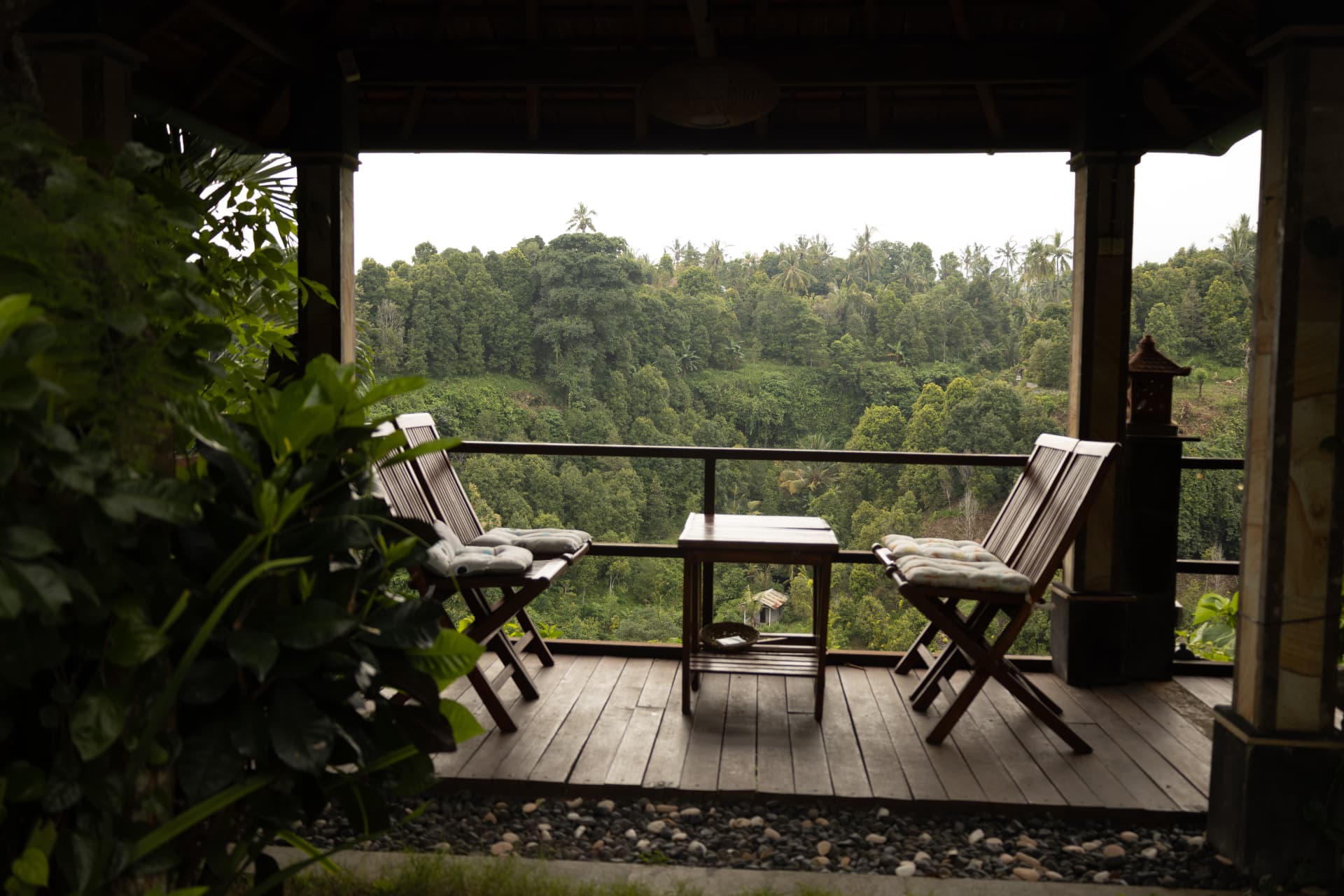 Covered terrace with wooden chairs overlooking the Balinese jungle valley