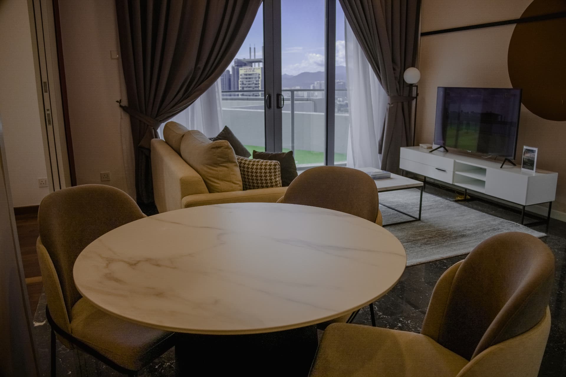 Marble dining table and lounge with skyline view from a high-rise suite