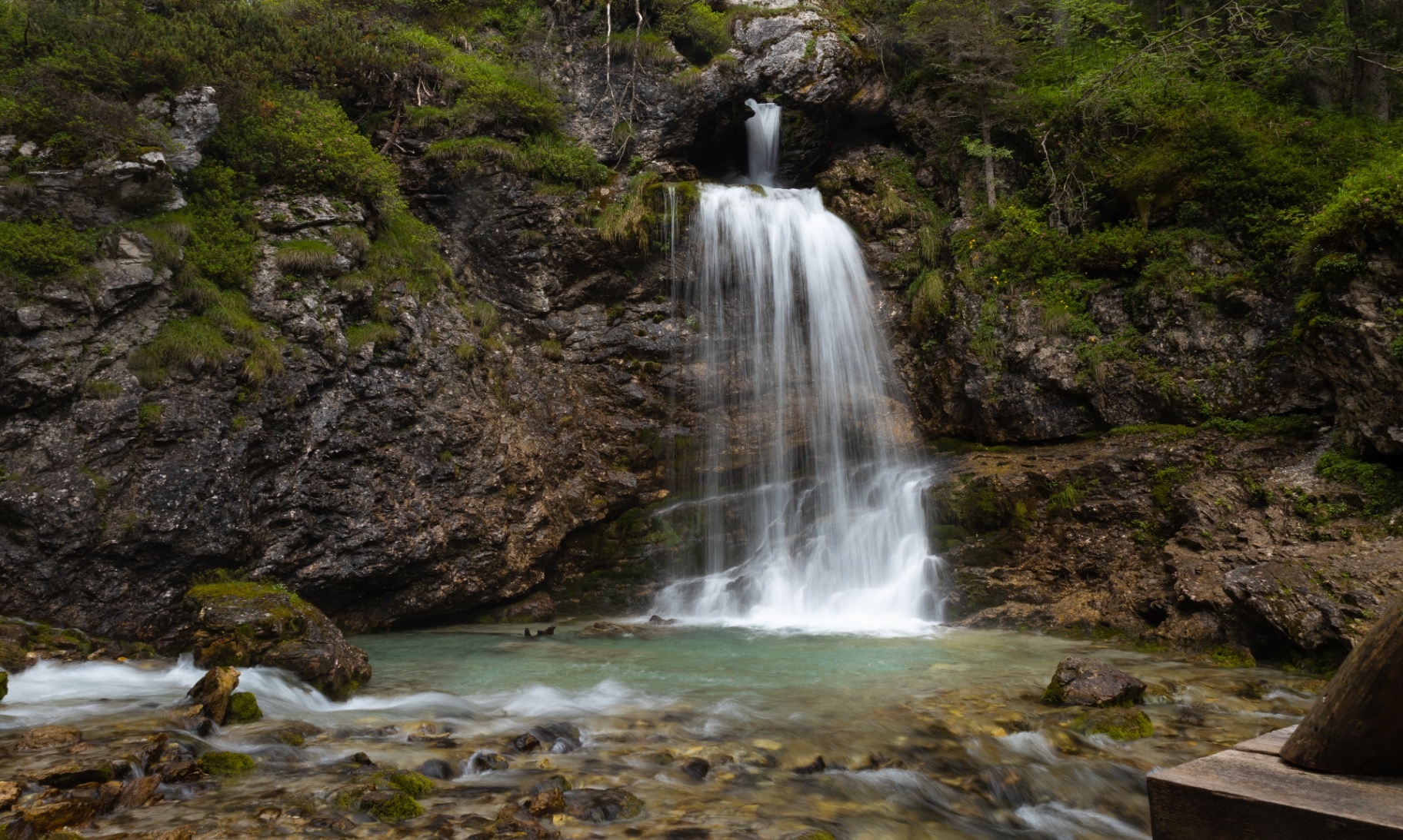 Alpine waterfall pouring into a turquoise pool