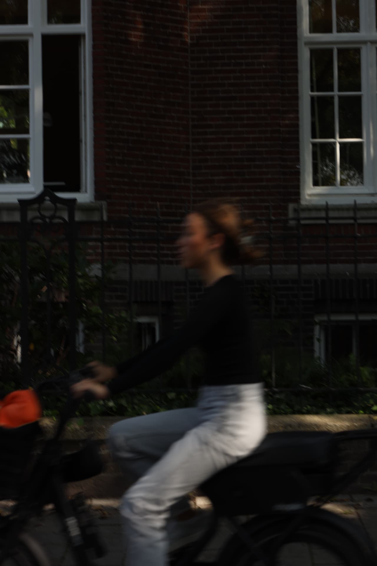 Motion-blurred cyclist passing a brick facade in Amsterdam