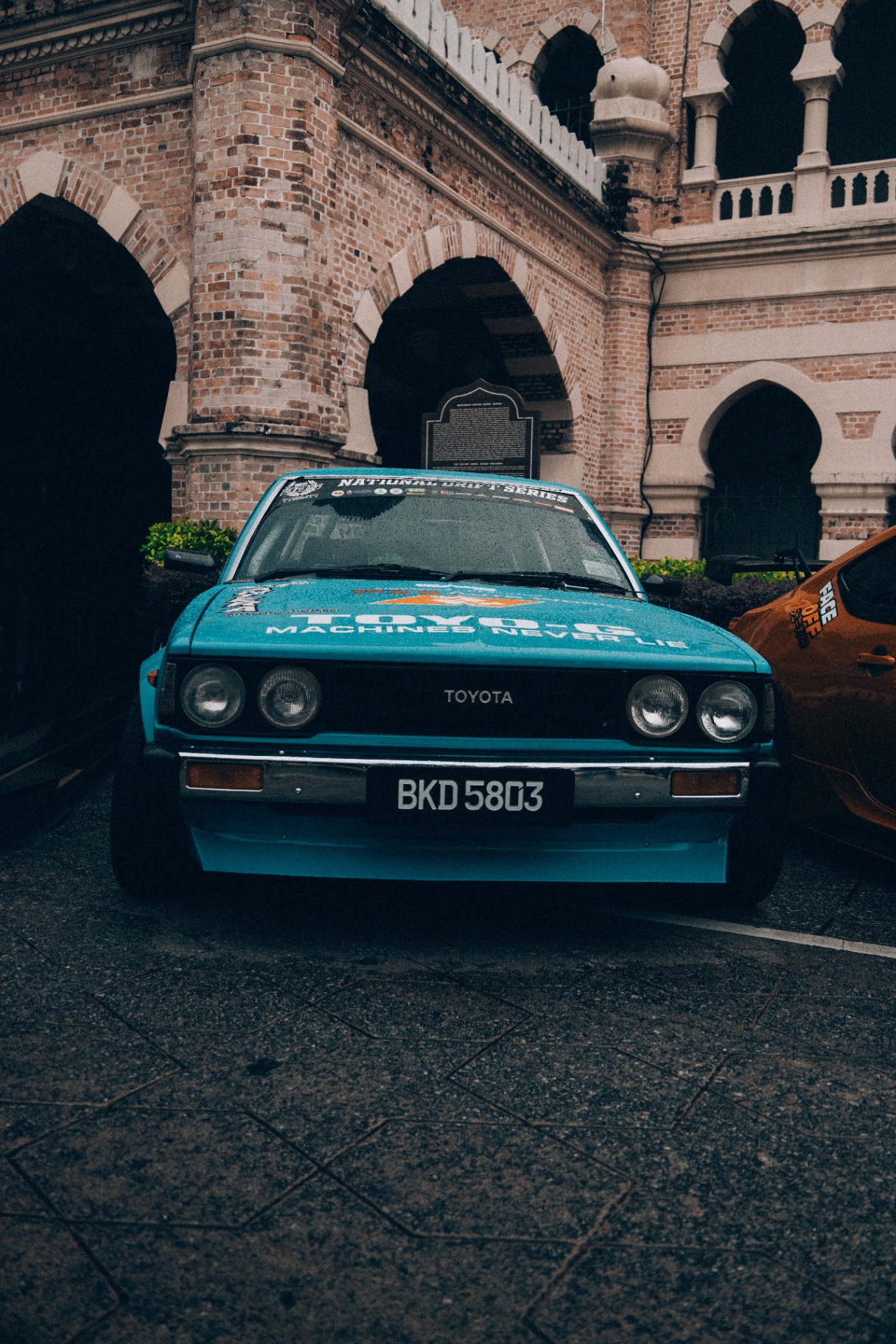 Classic teal Toyota drift car parked under colonial arches