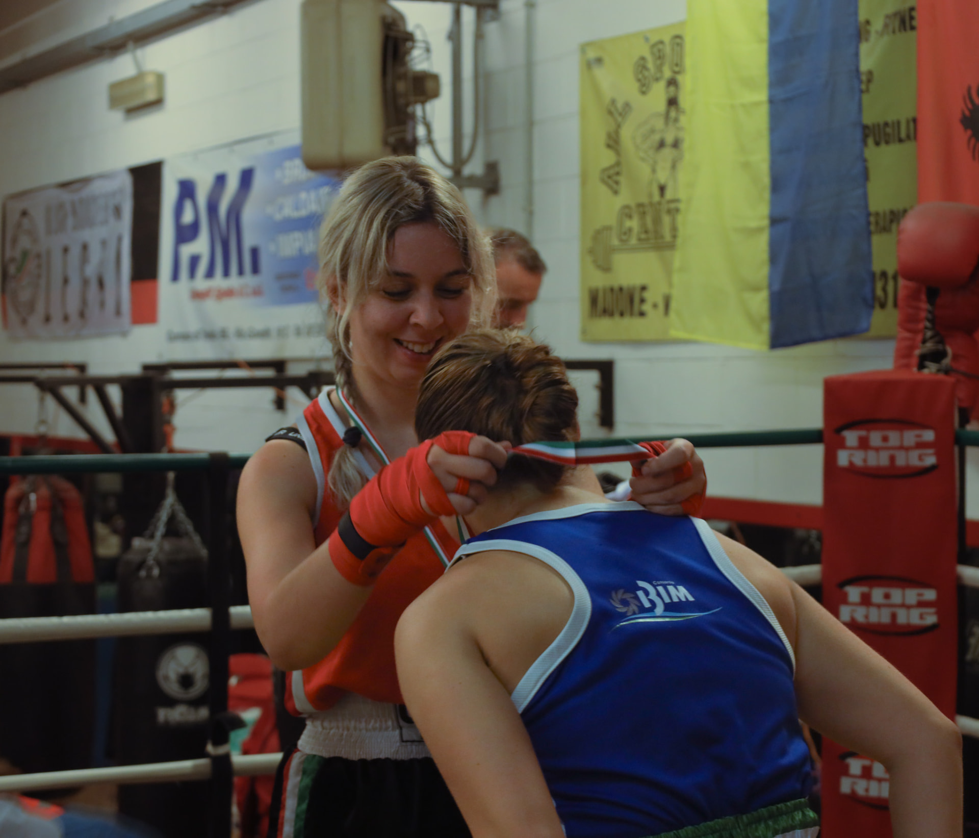 Coach placing a medal around a young boxer's neck in the ring
